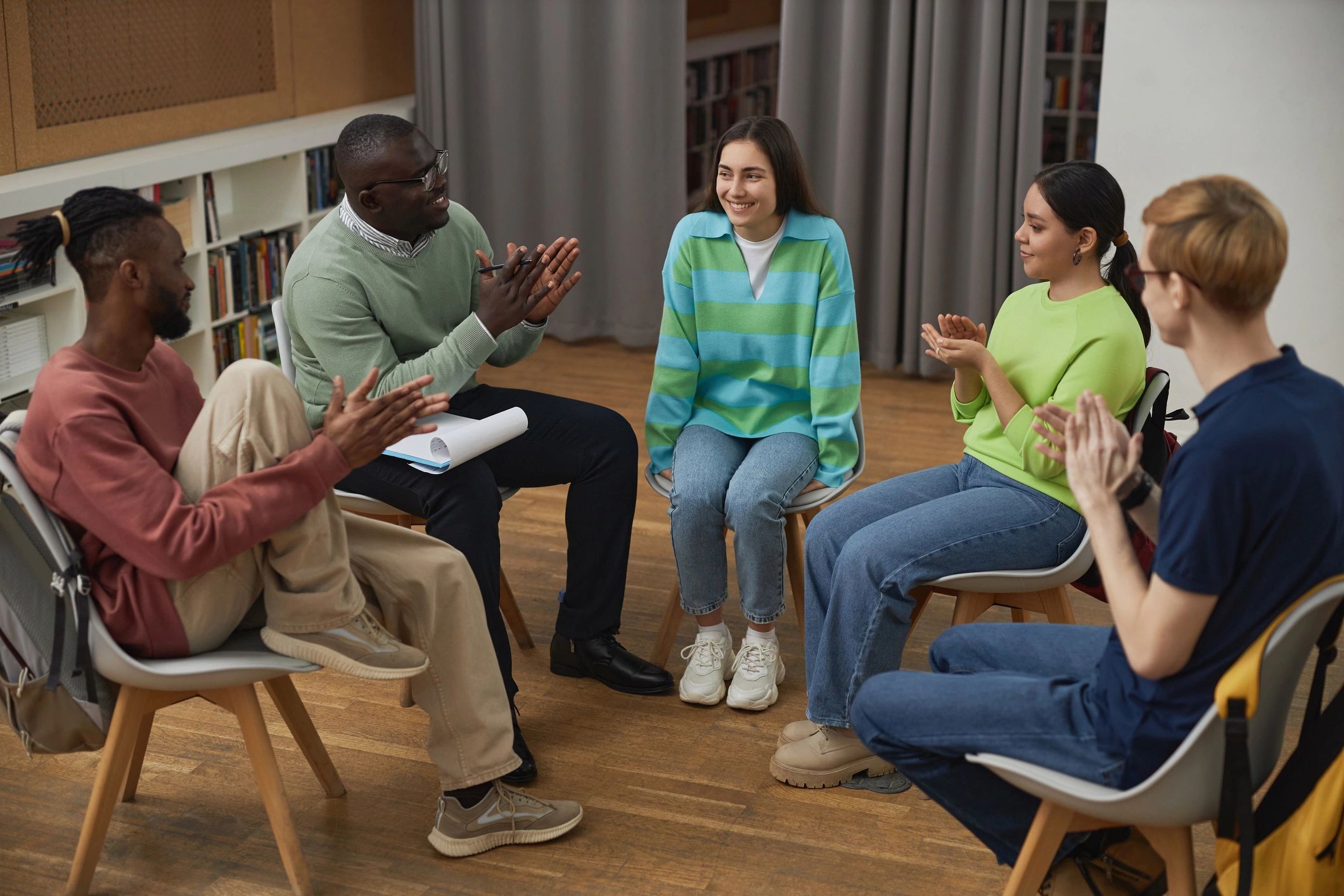 Diverse young people in a support group applauding together